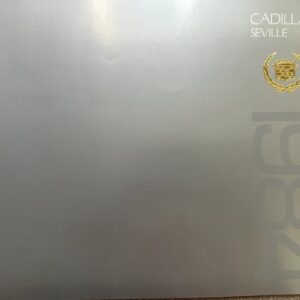 Metallic gray Cadillac Seville brochure cover with the white 'CADILLAC SEVILLE' text at the top right and a gold crest; large faded numbers run vertically along the right edge.