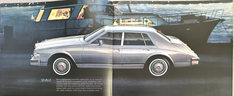 IMG_5806 | Merrick Auto Museum Side view of a silver Cadillac Seville in a print spread, with boats and a harbor in the background and the caption 'SEVILLE' nearby.