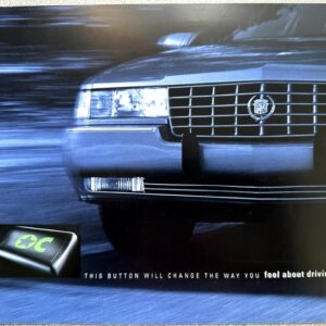 Front view of a silver Cadillac with motion blur, plus a small black control button with a green star inset in the lower-left corner, and the caption about changing how you feel about driving.