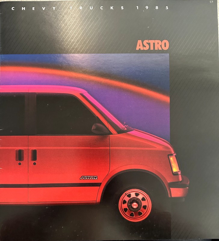 IMG_6095 | Merrick Auto Museum Red Chevrolet Astro van from the side, with 'ASTRO' text and 'Chevy Trucks 1985' on a dark background. Caption-style vehicle advertisement image.