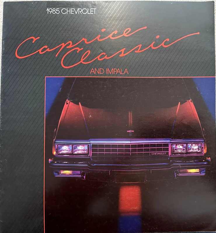 IMG_6098 | Merrick Auto Museum Brochure cover: 1985 Chevrolet Caprice Classic and Impala with a close-up of the front grille and headlights in red/blue lighting.
