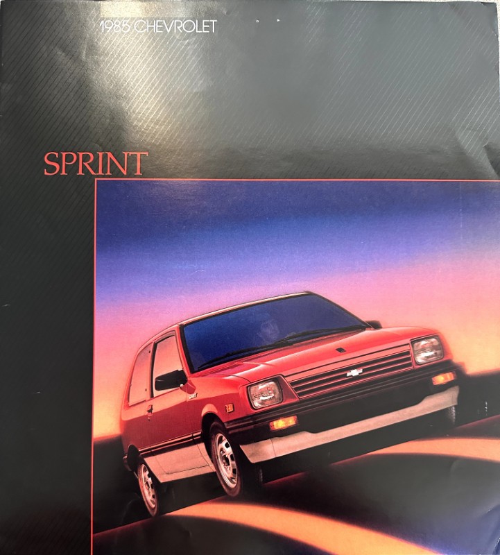 IMG_6107 | Merrick Auto Museum Brochure cover featuring a red 1985 Chevrolet Sprint with a sunset gradient background and the word SPRINT in red text at the top-left.