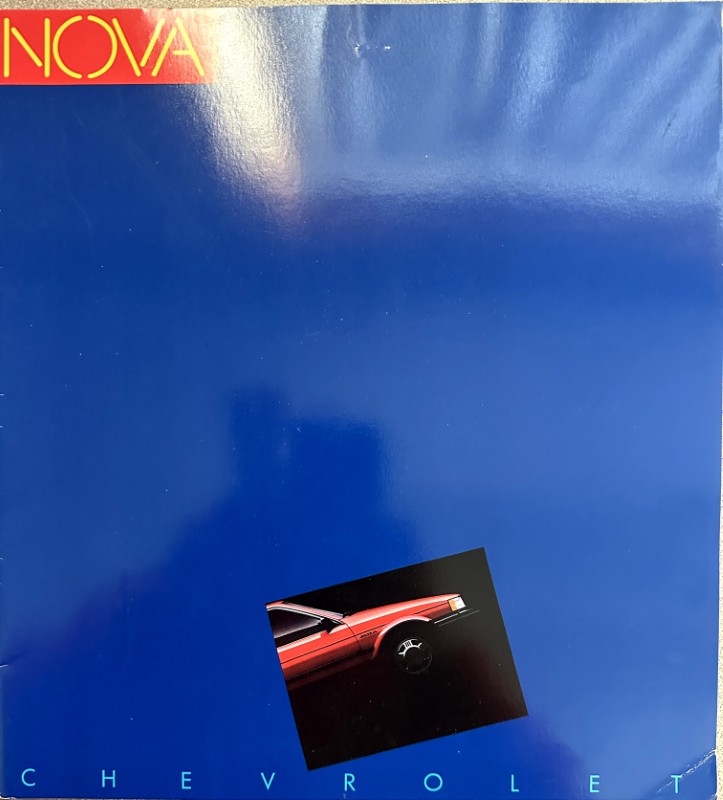 IMG_6122 | Merrick Auto Museum Blue NOVA cover with a small tilted photo of a red Chevrolet car near the bottom; CHEVROLET lettering along the bottom edge.