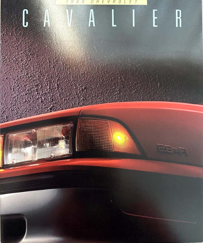 IMG_6146 | Merrick Auto Museum Close-up of the red Chevrolet Cavalier's front left corner, showing the headlight, amber turn signal, and '2.8 V6' badge.