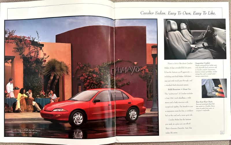 IMG_6181 | Merrick Auto Museum Advertisement spread showing a red Cavalier sedan parked near a colorful building with a cafe scene, plus interior and feature shots on the right page.