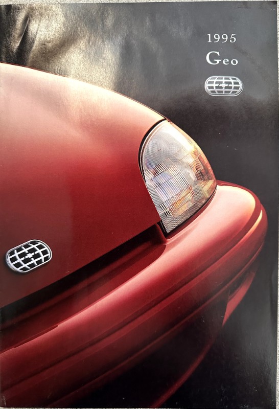 IMG_6219 | Merrick Auto Museum Close-up of a red car's front end with the headlight on the right and a 1995 Geo branding on the cover