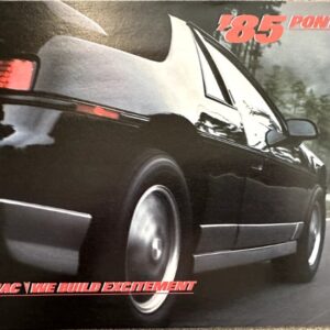 Rear three-quarter view of a black Pontiac on a winding road, with red '85 Pontiac' text and 'Pontiac We've built excitement' slogan.