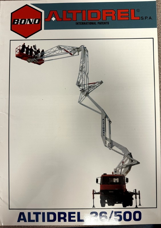 IMG_7246 | Merrick Auto Museum Aerial work platform with a long white boom lifting a red work basket high above the ground, Altidrel branding nearby, against a pale backdrop.