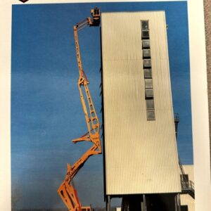 Orange articulated boom lift extended beside a tall white industrial building, used for maintenance, with Altidrel 32/500 branding visible above.