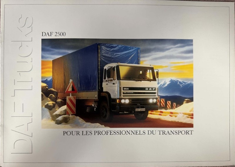 IMG_7300 | Merrick Auto Museum DAF 2500 truck with a blue-covered trailer on a rocky desert road, mountains in the background; caption: 'Pour les professionnels du transport'