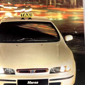 Front view of a beige Fiat Marea taxi with a yellow TAXI sign on the roof, city lights blurred behind it (Fiat Taxi Program brochure).