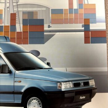 Blue Fiat Fiorino front view against a shipping yard illustration with stacked cargo containers in the background.