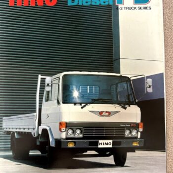 Front view of a white Hino FD 4x2 truck parked in front of a modern building, with bold 'HINO Econo Diesel FD' branding above.