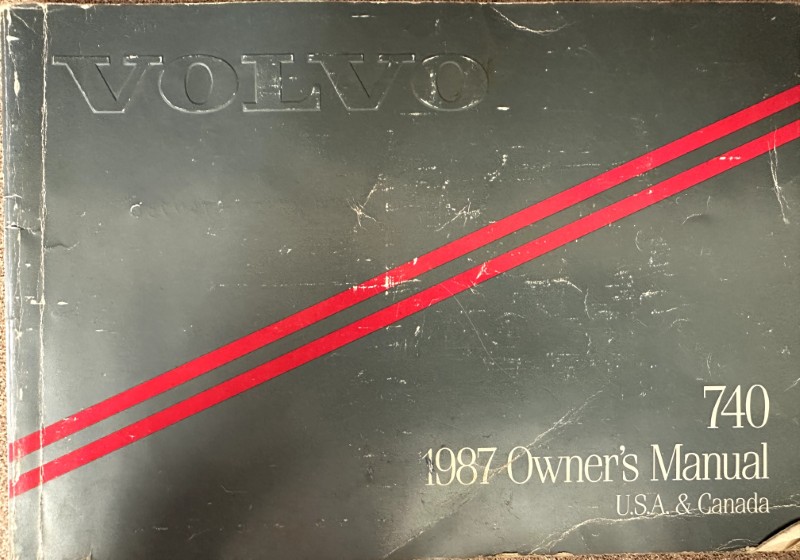 IMG_8703 | Merrick Auto Museum Volvo 740 1987 Owner's Manual cover for USA & Canada, dark cover with two red diagonal stripes.
