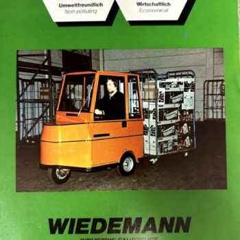 IMG_8738 | Merrick Auto Museum Green Wiedemann industrial equipment brochure featuring an orange electric forklift pulling a rack of boxed goods in a warehouse setting.