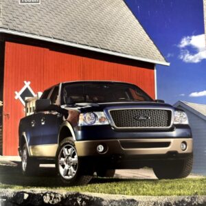 2008 Ford F-150 pickup truck in blue and tan parked in front of a red barn with a stone wall in the foreground.