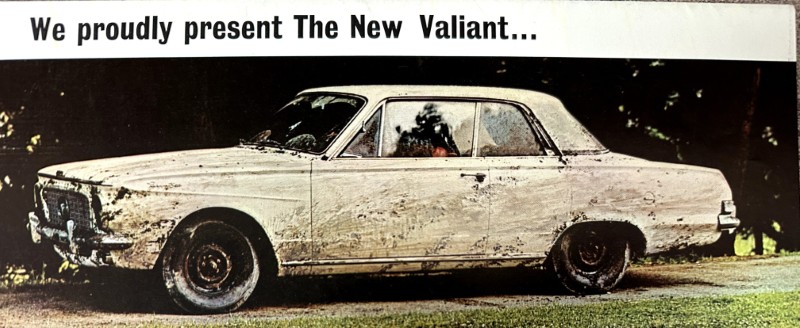IMG_9139 | Merrick Auto Museum White vintage sedan splattered with mud, parked on grass, with a banner above reading 'We proudly present The New Valiant...'