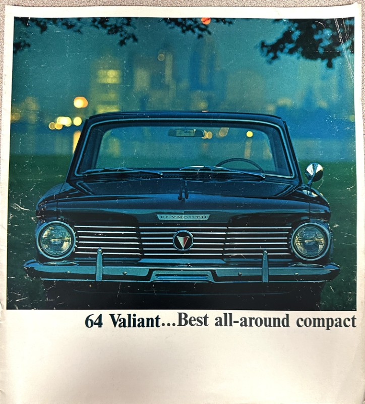 IMG_9151 | Merrick Auto Museum Front view of a dark blue 1964 Plymouth Valiant with a chrome grille; the caption beneath reads '64 Valiant... Best all-around compact'