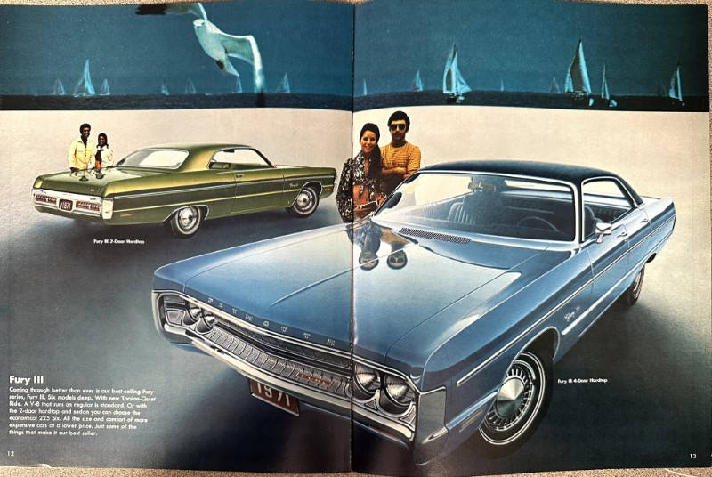 IMG_9207 | Merrick Auto Museum Blue 1960s Fury car in foreground with chrome grille, two-door hardtop; green Fury behind; couple standing by the vehicles in a magazine ad spread with sailboats in the background.