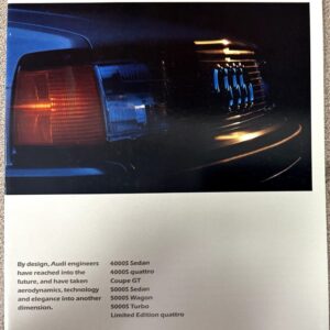 Close-up of an Audi car's front end—grille, headlight, and bumper, from a 1985 brochure page with model list below.