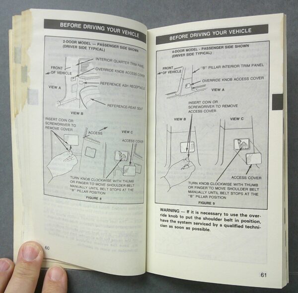 Digital Camera | Merrick Auto Museum Open instruction manual showing two pages with vehicle-preparation diagrams and the header 'BEFORE DRIVING YOUR VEHICLE' at the top of each page; left page covers 2-door models, right page 4-door, with labeled views and steps for removing covers and adjusting seats.