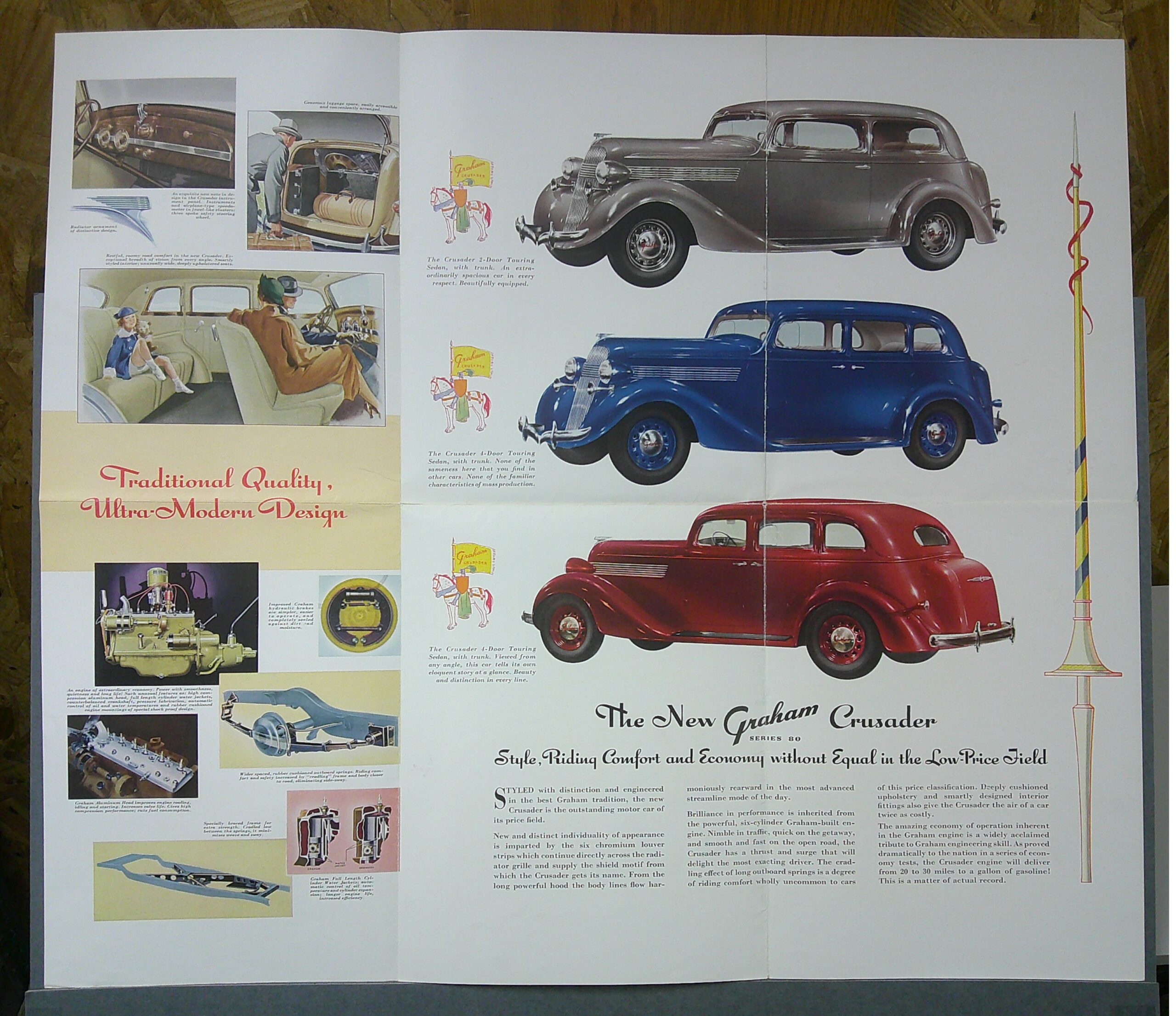 Digital Camera | Merrick Auto Museum Vintage car advertisement spread showing large illustrations of classic Graham cars (gray sedan at top, blue car below) with smaller inset panels of interiors and engine diagrams; decorative text and slogans run across the pages.