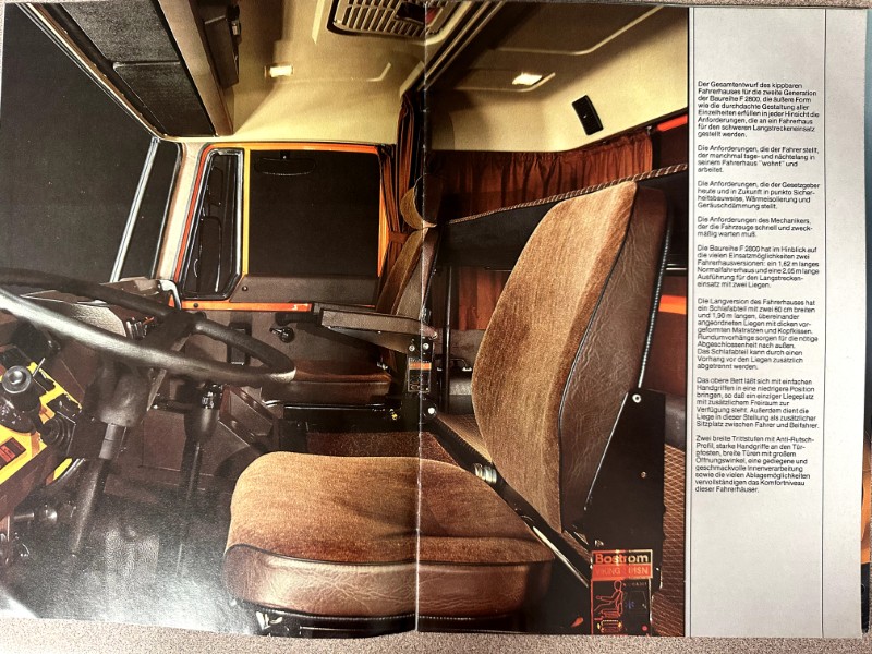 IMG_0018 | Merrick Auto Museum Interior of a vintage truck cab: brown fabric seats, steering wheel, and dashboard, with a tall German instruction panel along the right wall
