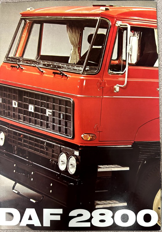 IMG_0028 | Merrick Auto Museum Front view of a red DAF 2800 truck showing the grille, two pairs of round headlights, and side mirror with a partial banner reading 'DAF 2800' at the bottom.
