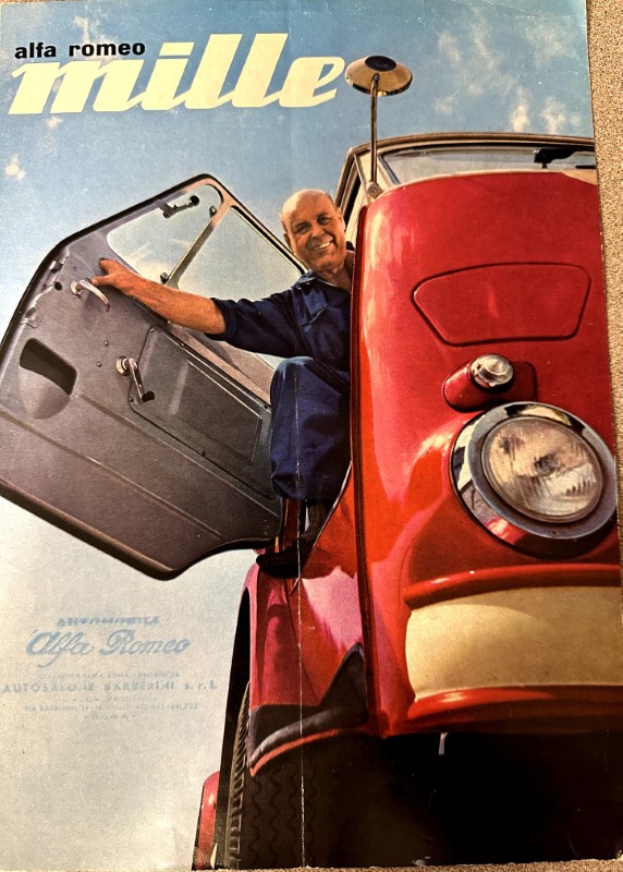 IMG_9489 | Merrick Auto Museum Cover for an Alfa Romeo Mille brochure: a smiling man steps from a red vintage car with its door open against a blue sky backdrop.
