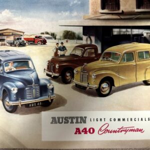 Three vintage Austin A40 Countryman vans in a dealership yard, blue, brown, and yellow, with a building and sign reading 'AUSTIN Light Commercials A40 Countryman'