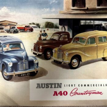 IMG_9533 | Merrick Auto Museum Three vintage Austin A40 Countryman vans in a dealership yard, blue, brown, and yellow, with a building and sign reading 'AUSTIN Light Commercials A40 Countryman'