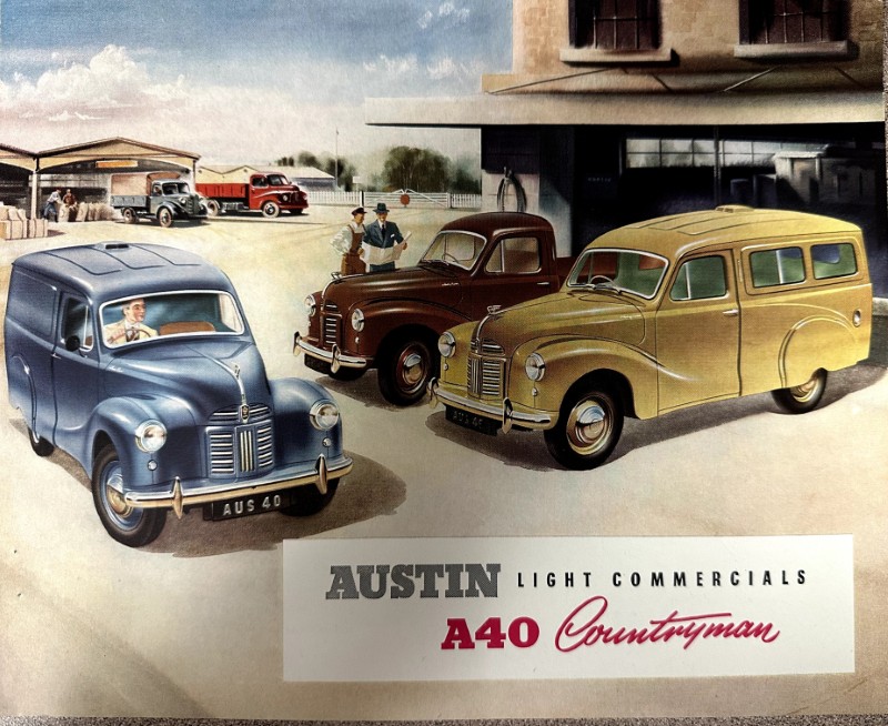 IMG_9533 | Merrick Auto Museum Three vintage Austin A40 Countryman vans in a dealership yard, blue, brown, and yellow, with a building and sign reading 'AUSTIN Light Commercials A40 Countryman'