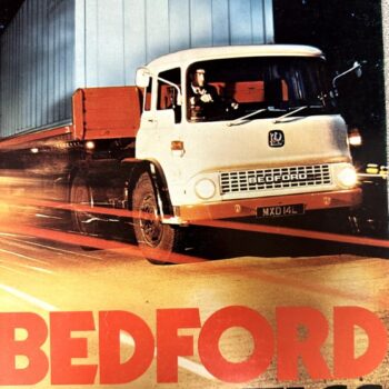 Vintage poster featuring a white Bedford TK truck pulling a tall blue trailer on a nighttime road shot; bold red lettering at bottom reads 'BEDFORD'.