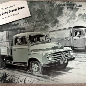 IMG_9709 | Merrick Auto Museum Vintage Borgward advertisement showing a light-duty diesel truck on a rural road with a flatbed trailer in the foreground and another truck in the background.