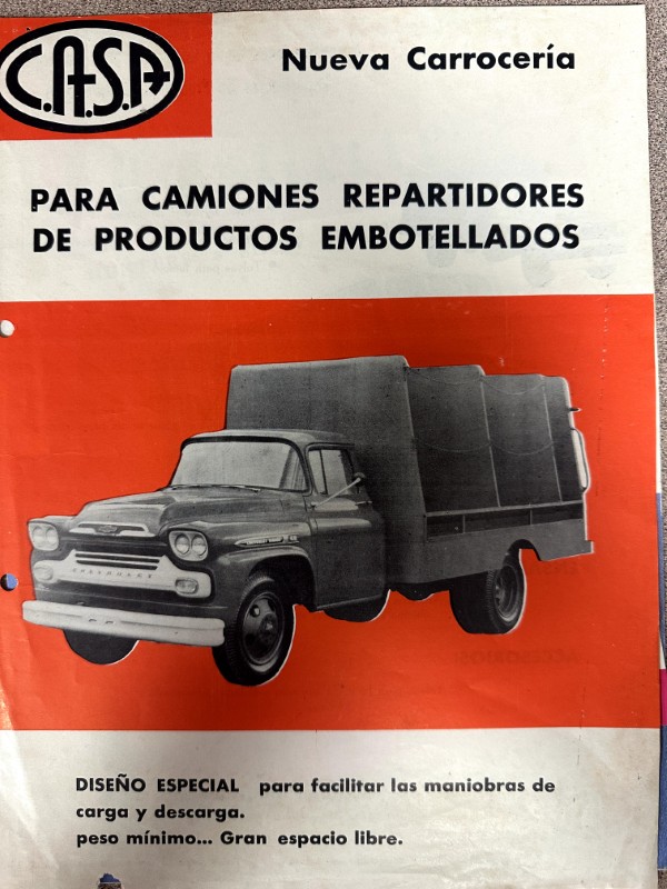 IMG_9836 | Merrick Auto Museum Vintage ad poster for delivery trucks, showing a classic gray cargo truck on an orange background with bold Spanish text.